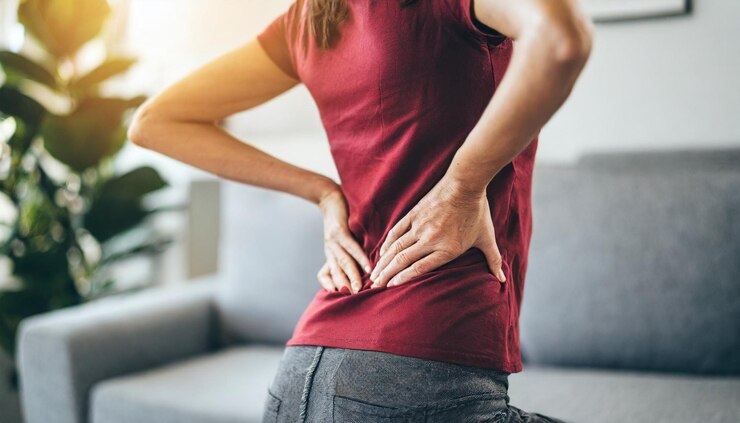 Photo woman grimaces in pain clutching lower back symbolizing discomfort and health issues