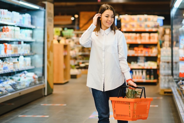 Женщина делает покупки в продуктовом магазине и выглядит очень счастливой