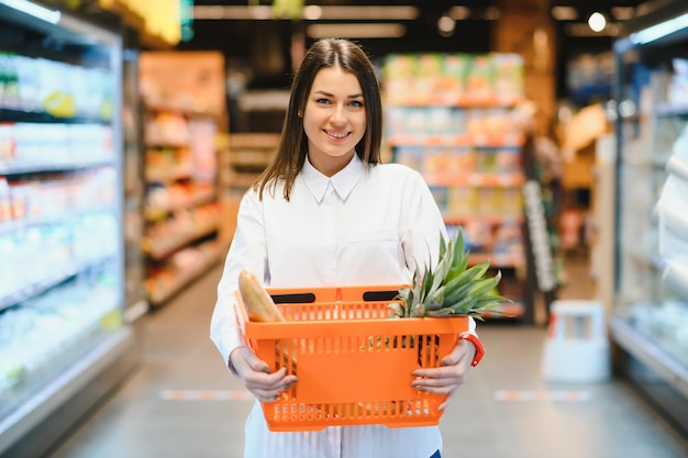 Женщина делает покупки в продуктовом магазине и выглядит очень счастливой