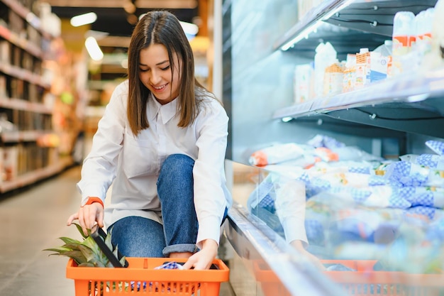 Женщина делает покупки в продуктовом магазине и выглядит очень счастливой