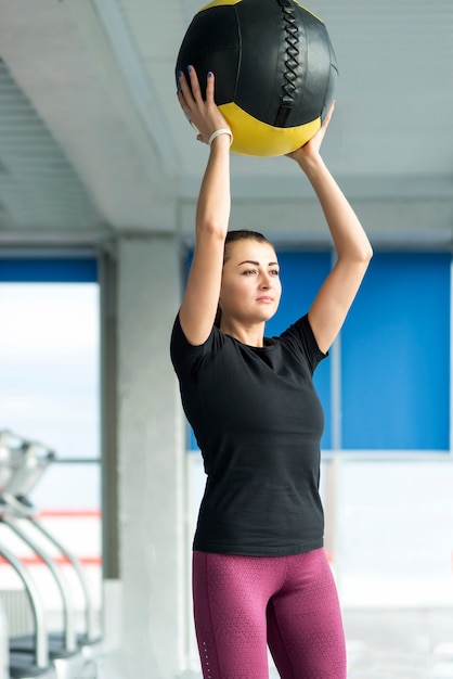 Woman in gym relaxing with medicine ball