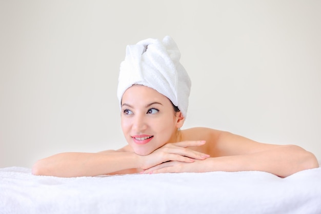 Woman hair wrapped in towel while looking away against white background