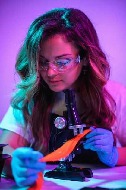 女性美容師のカラーリストが顕微鏡を使って髪の構造を調べます。クローズアップ、セレクティブフォーカス。
