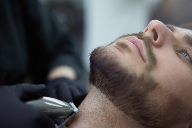 Woman hairdresser cut beard handsome caucasian young man