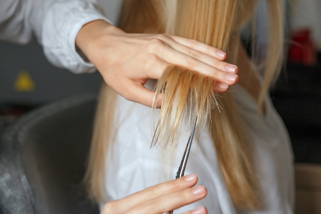 Parrucchiere donna che taglia i capelli biondi del cliente dopo la morte. primo piano