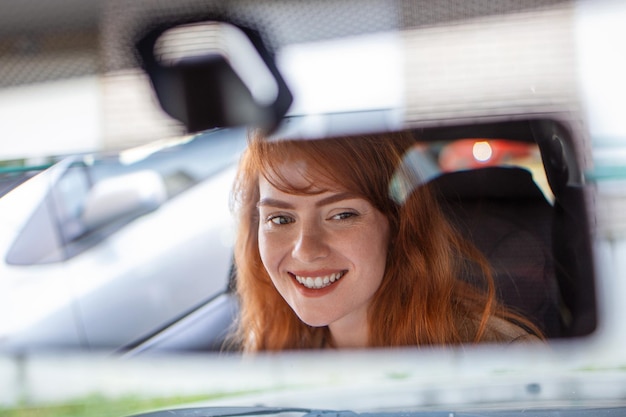 Woman hand adjusting rear view mirror of her car Happy young woman driver looking adjusting rear view car mirror making sure line is free visibility is good