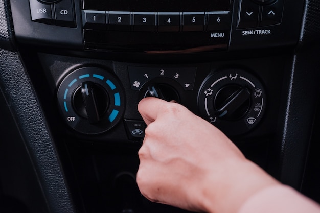 Woman hand on the air conditioner button in the car