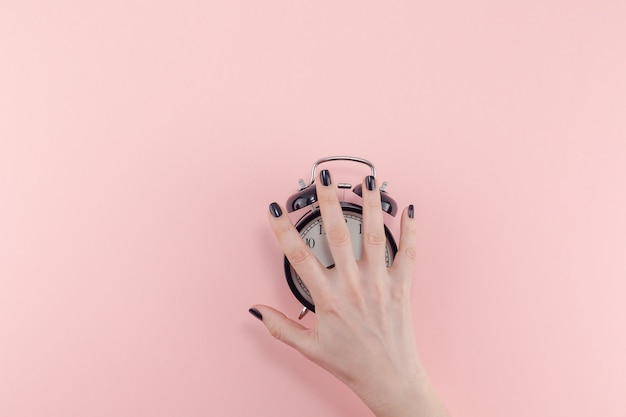 Woman hand and alarm clock