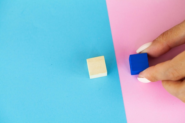 Woman hand arranging empty wood block and copy space on blue and pink background