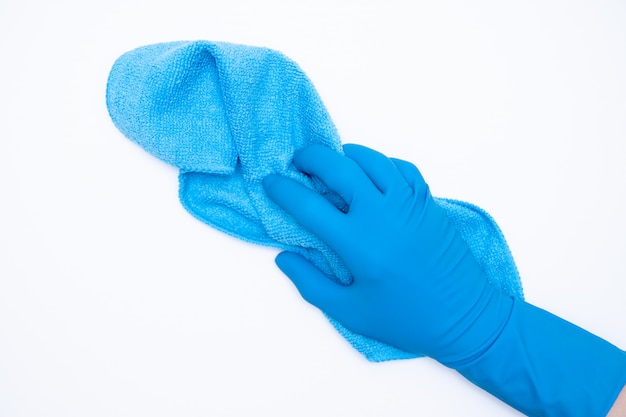 La mano della donna in guanti di gomma blu tiene lo straccio su bianco.