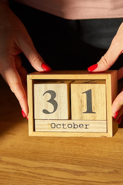 Foto il cambio di mano della donna imposta la data sul calendario di legno a ottobre