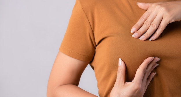 Woman hand checking lumps on her breast for signs of breast cancer concept