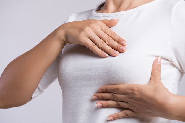 Woman hand checking lumps on her breast for signs of breast cancer