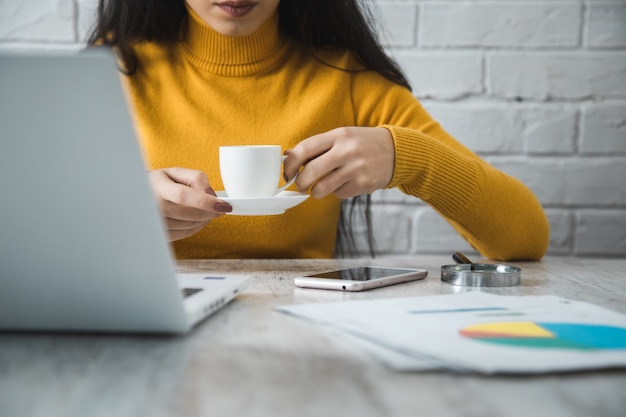 オフィステーブルの背景に女性の手コーヒー