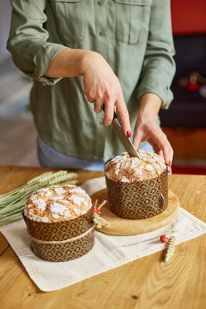 Woman hand cut Easter cake on wooden rustic table