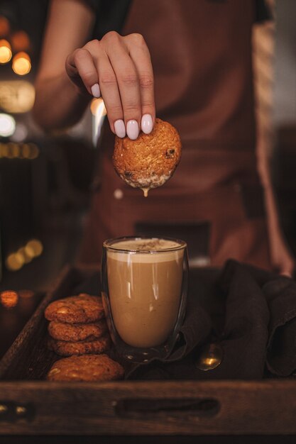 Foto biscotto di immersione della mano della donna nel caffè