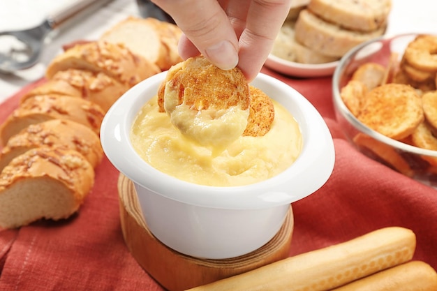 Photo woman hand dipping toast in beer cheese dip