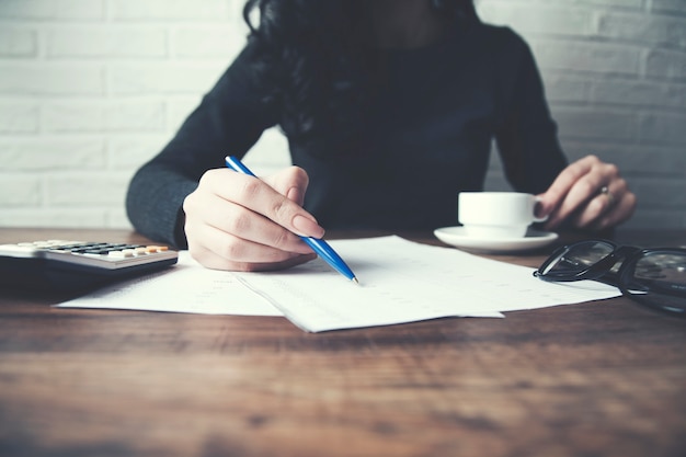 Woman hand document and calculator on table