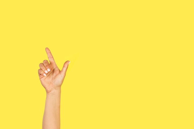 Foto mano della donna che fa gesto di celebrazione su sfondo giallo