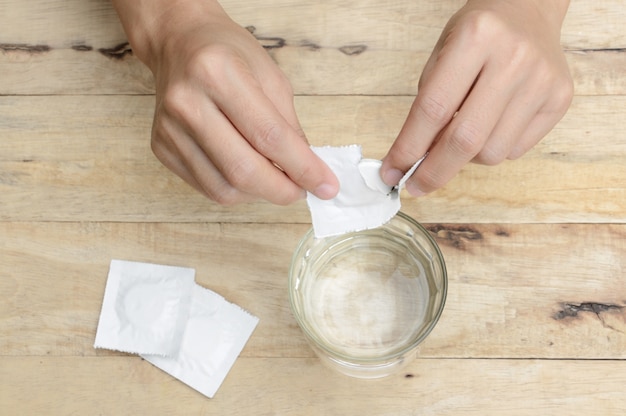 Photo woman hand dropping effervescent tablet in a glass of water on wooden table