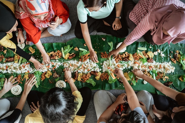 Woman hand eating their food together laying on banana leaf