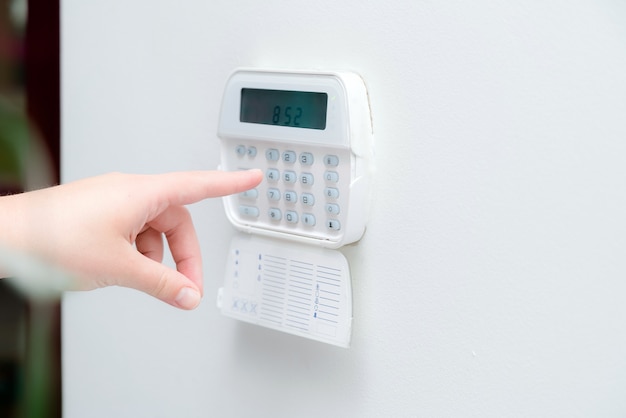 Woman hand entering alarm system password of an apartment, house of business office. Surveillance and protection console against rubbery and thief