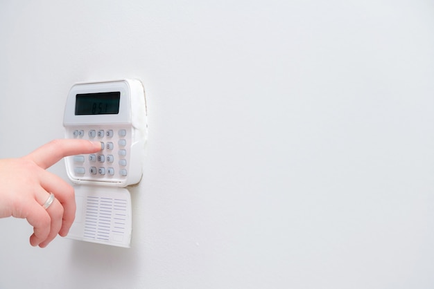 woman hand entering alarm system password of an apartment, house or business office.