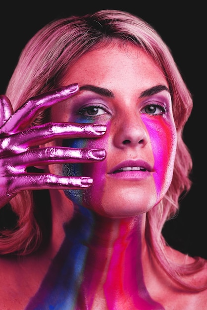 Woman hand on face and beauty portrait with metallic color paint cosmetics on skin in studio Female model person on a black background for art deco fantasy and creative makeup with a neon light