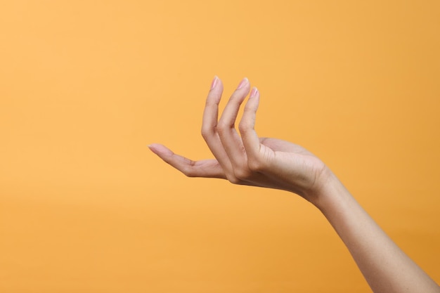Женский жест руки, изолированный на желтом фоне студии