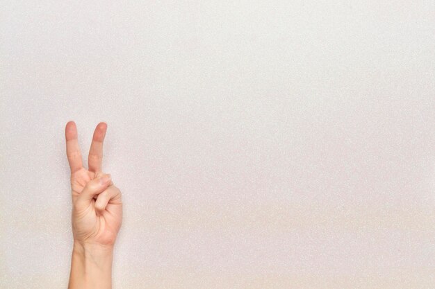 Woman hand gesture of peace and victory on white bright background