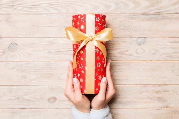 Woman hand give Valentine gift box, top view