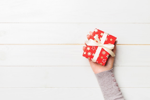 Woman hand give Valentine gift box, top view