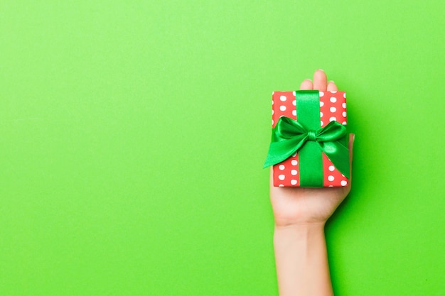 Woman hand give Valentine gift box, top view