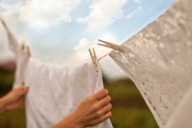 Woman hand hanging up laundry outdoor in a sunny day