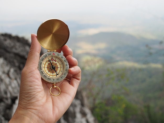 woman hand hold compass on top mountain