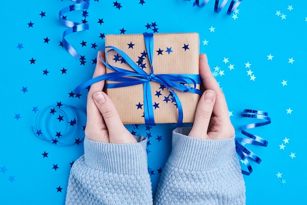 Woman hand hold gift box wrapped in kraft paper