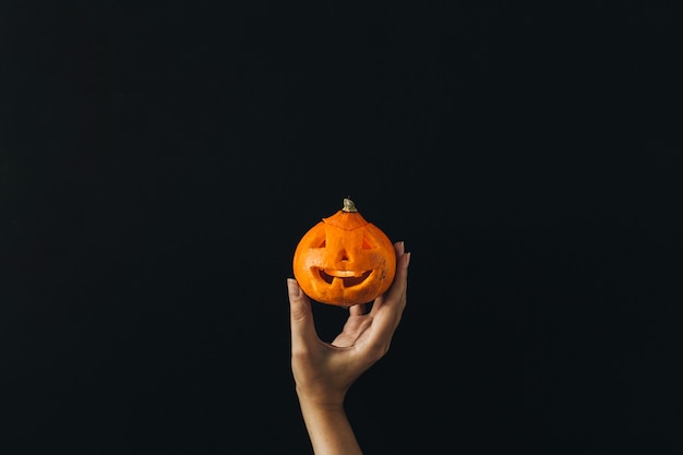 Woman hand hold Halloween pumpkin on black surface