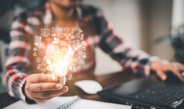 Foto la lampadina della presa della mano della donna con le icone lavora sulla scrivania la creatività e l'innovazione sono le chiavi del successo concetto di nuova idea e innovazione con le icone e le lampadine risparmia il denaro libertà di pensiero