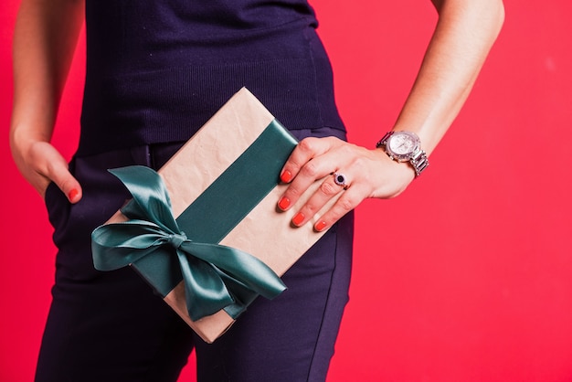 Woman hand hold one present at studio pink background