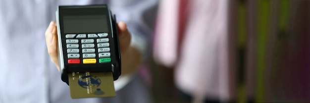 Woman hand hold POS termimal with gold plastic debit card