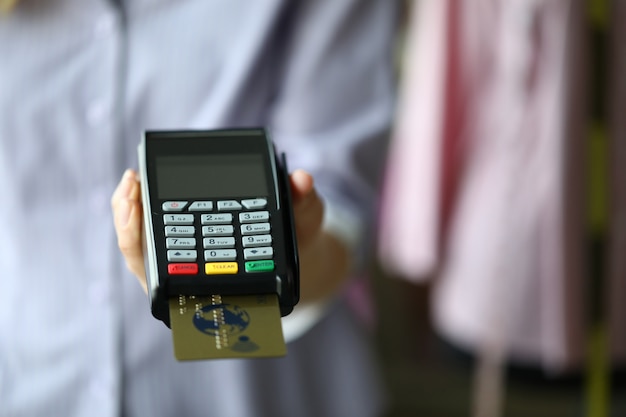 Woman hand hold POS termimal with gold plastic debit card