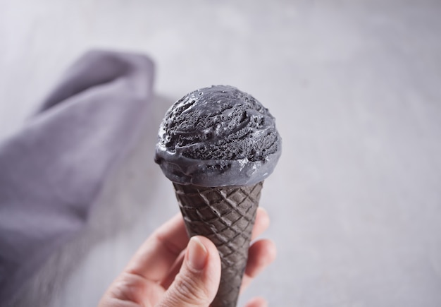 Woman hand holding black ice-cream in hand