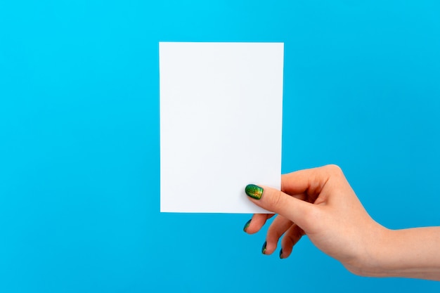 Woman hand holding blank card on blue background