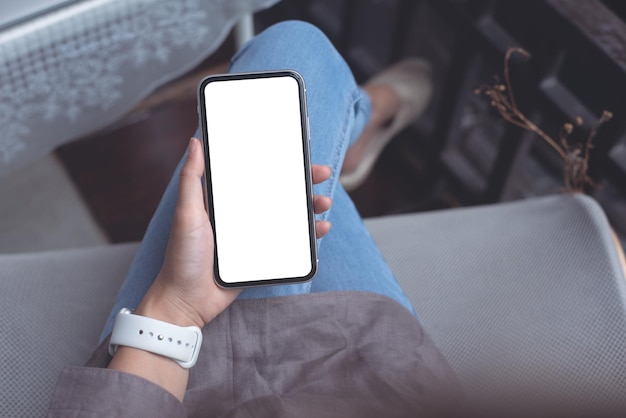 Foto mano della donna che tiene il telefono cellulare dello schermo in bianco a casa o nella caffetteria