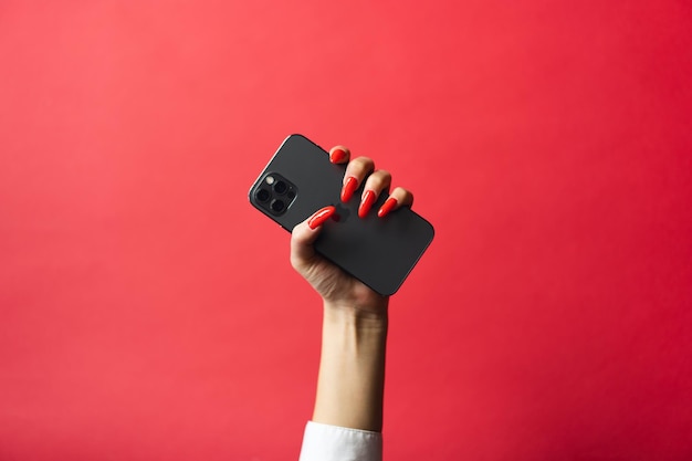 Photo woman hand holding a blank screen smart phone on red background with clipping path