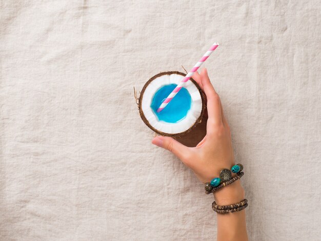 Woman hand holding a blue cocktail with straw 