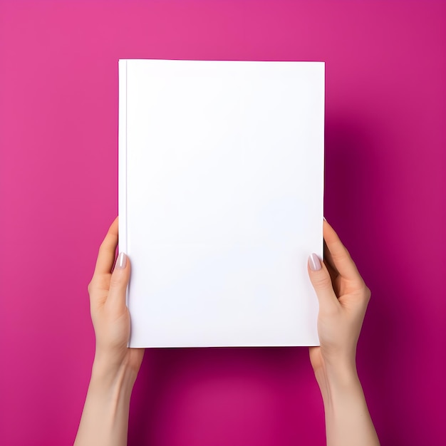 Woman hand holding book with blank cover on pink background top view