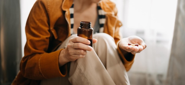 Фото Женщина держит в руках бутылку с таблетками и собирается принимать лекарства, прописанные врачомxa