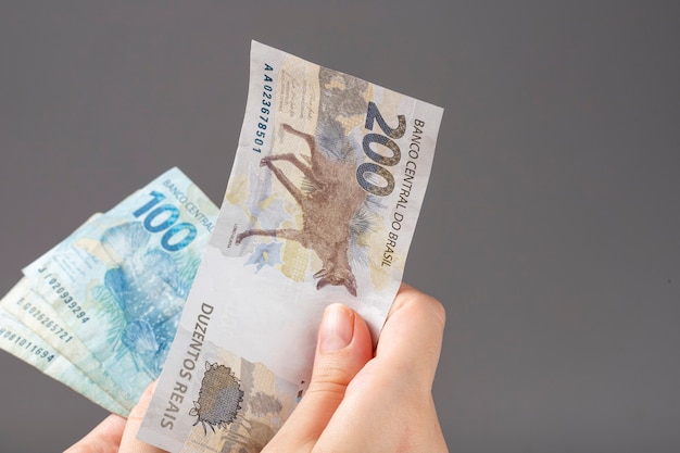 Woman hand holding Brazilian banknotes