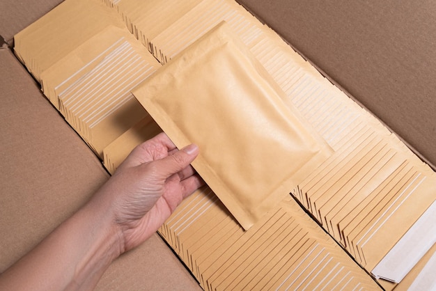 写真 郵便輸送のためのバブル封筒を持っている女性の手
